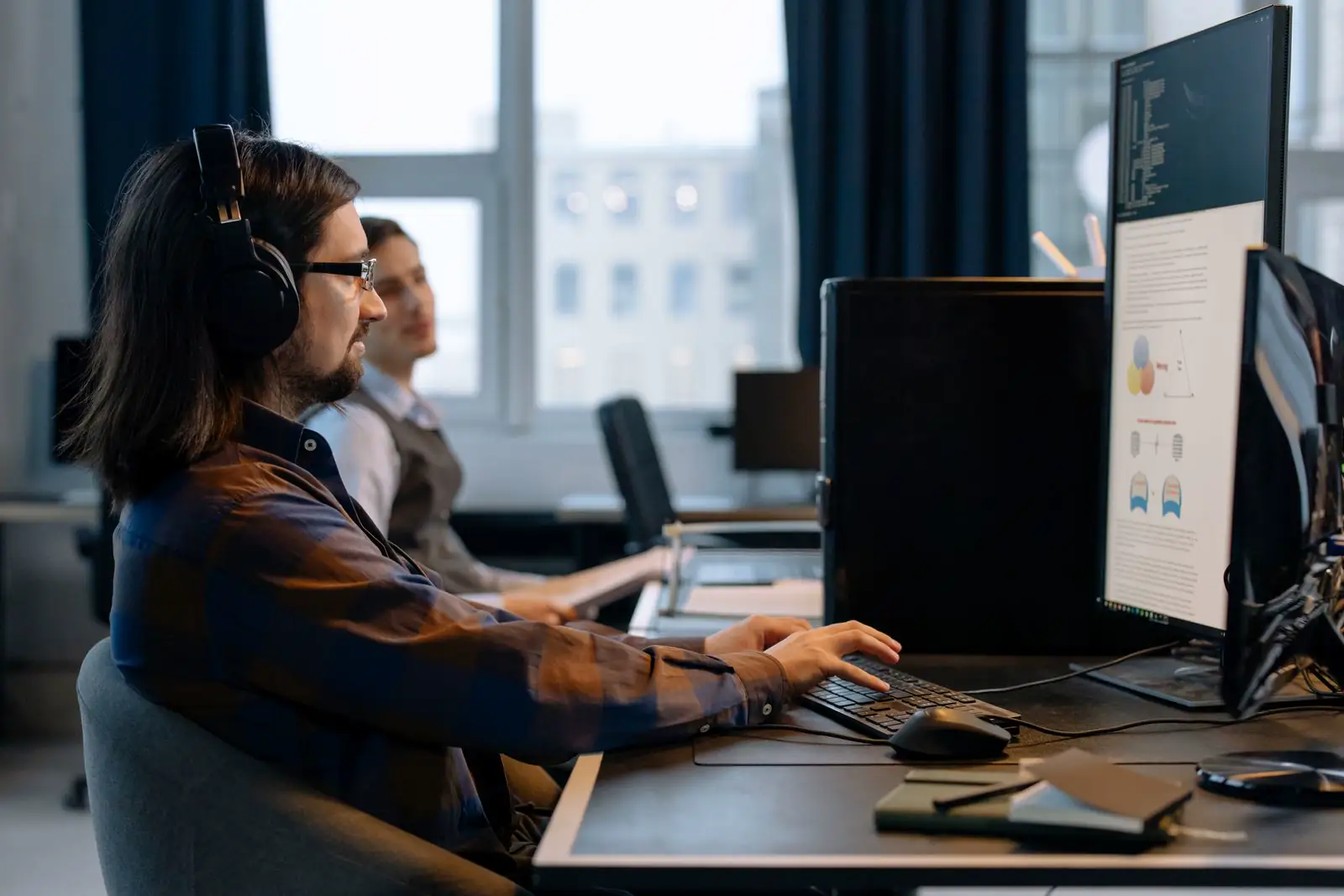 Profesional con auriculares trabajando en computadora con software de gestión en pantalla
